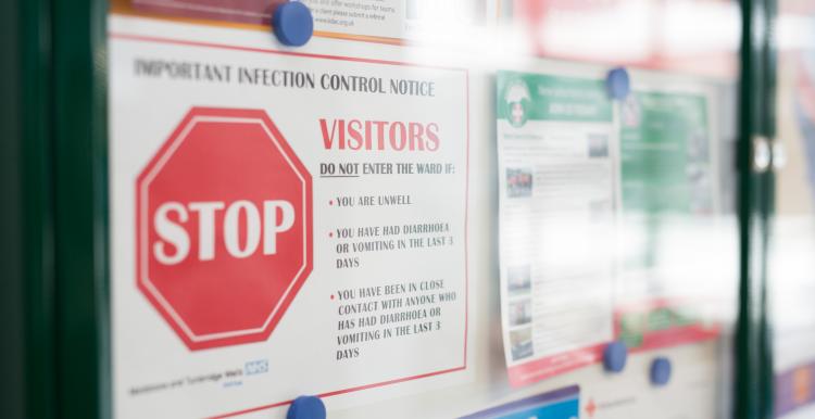 Image of a noticeboard in a health service, with a sign warning about infection control