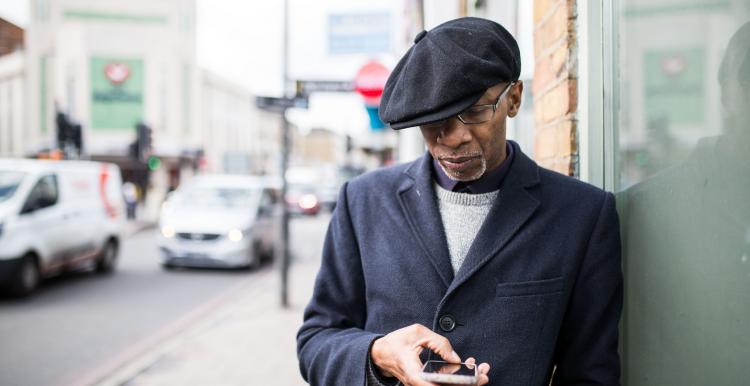 black elderly man outside on phone hat