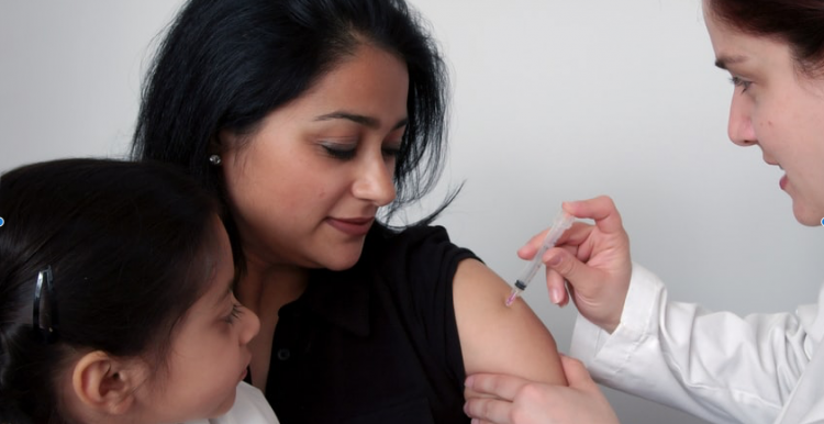 Lady with a child on her lap receiving COVID vaccine