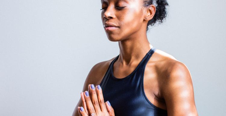 women in yoga pose black sports bra prayer hands