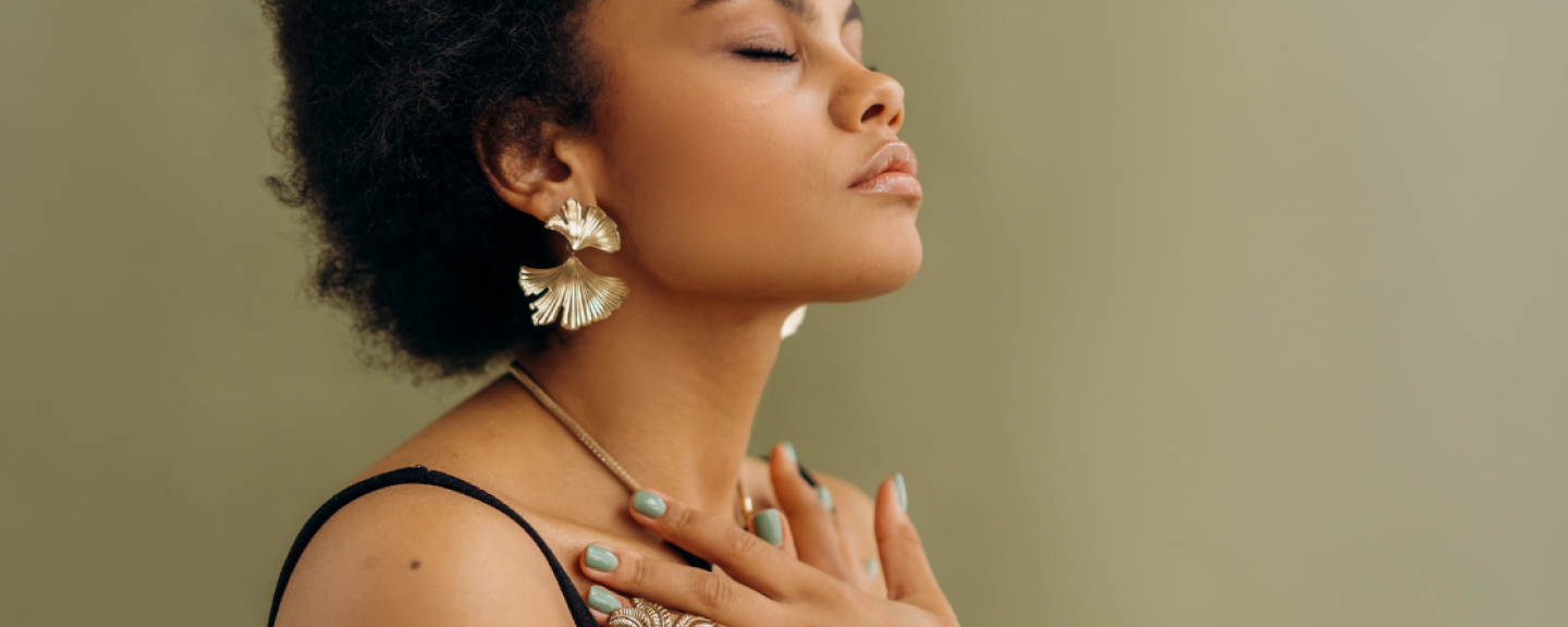 Black woman with closed eyes, hands on the chest meditating