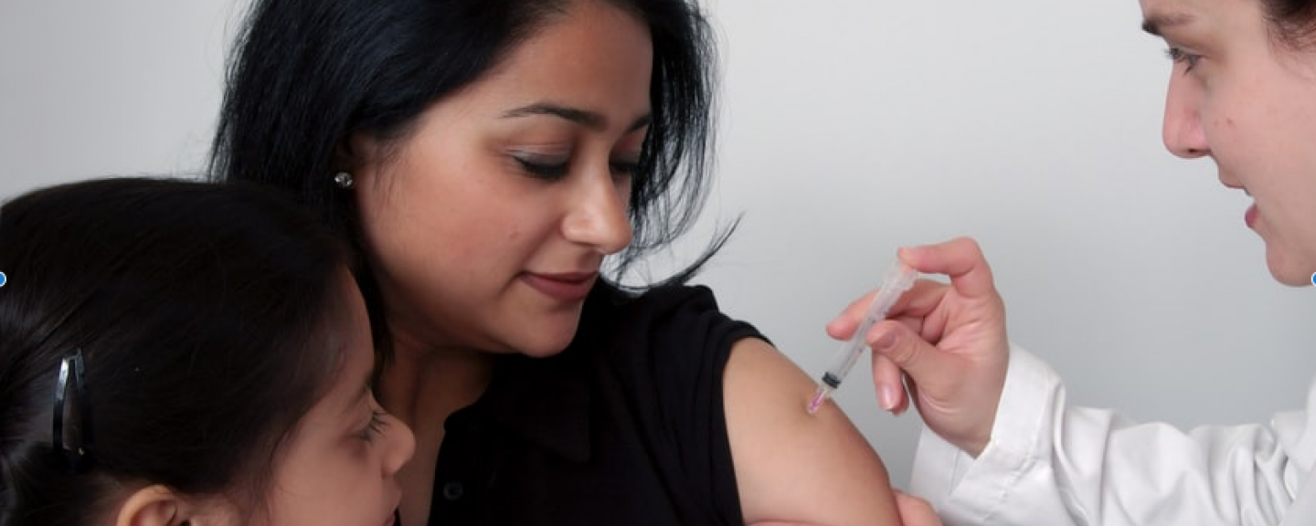 Lady with a child on her lap receiving COVID vaccine