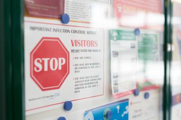 Image of a noticeboard in a health service, with a sign warning about infection control