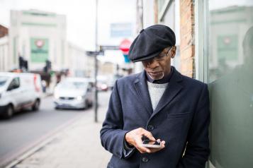 black elderly man outside on phone hat