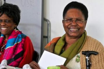 two older ladies sitting next to each other smiling at camera