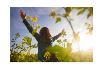Woman holding arms up to the sky in field of flowers