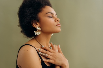 Black woman with closed eyes, hands on the chest meditating