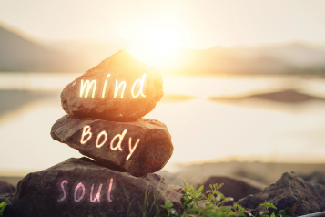 Mind Body Spirit light written on rocks, sunset in the background