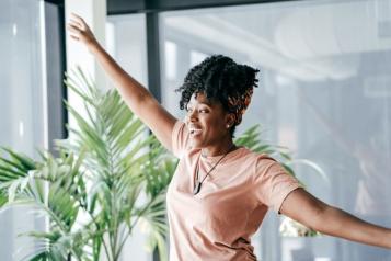 Black woman spreads her arms, smiling