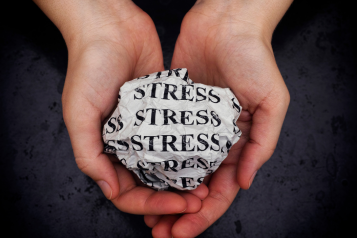 hands holding a paper ball with stress written on it