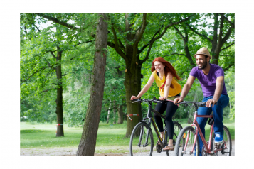2 people riding bikes in a park