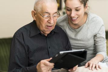 Woman helping an elderly man use a IPad