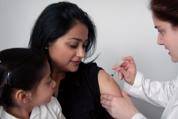 Lady with a child on her lap receiving COVID vaccine