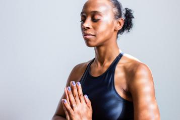 women in yoga pose black sports bra prayer hands