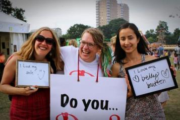 ladies in a park, holding signs with confidence quotes.