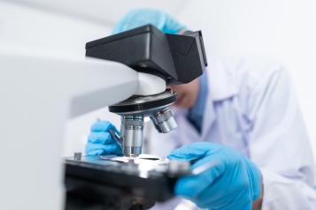 Person leaning over a microscope in a scientific laboratory