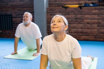 An older man and woman doing yoga together on colourful mats