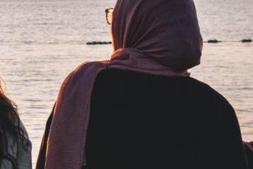 back of a lady in a hijab looking at the sunset