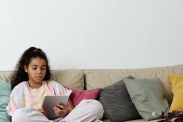 girl sitting on sofa using tablet