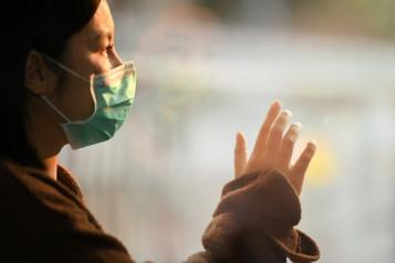 Girl wearing mask looking out of a window