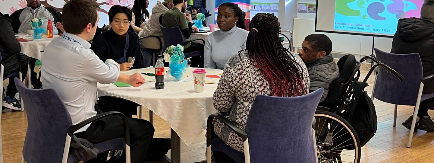 People having a conversation whilst seated around a table.