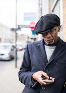 black elderly man outside on phone hat